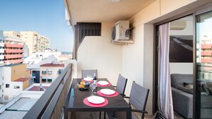 Un balcon avec une table à manger pour quatre personnes, des chaises et une vue sur le paysage urbain.
