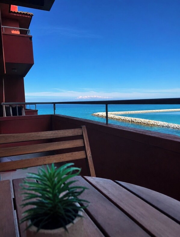 A balcony with a wooden bench and a potted plant, overlooking a clear blue sea and a rocky shoreline. - Casa Filippa with a terrace overlooking the sea (Balestrate)