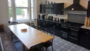 A kitchen with a wooden table, chairs, black cabinets, a stove, and a window. - MANSION WITH SWIMMING POOL, GAMES ROOM, SEA VIEWS, SANDY BEACHES 2 MINS WALK (Ryde)