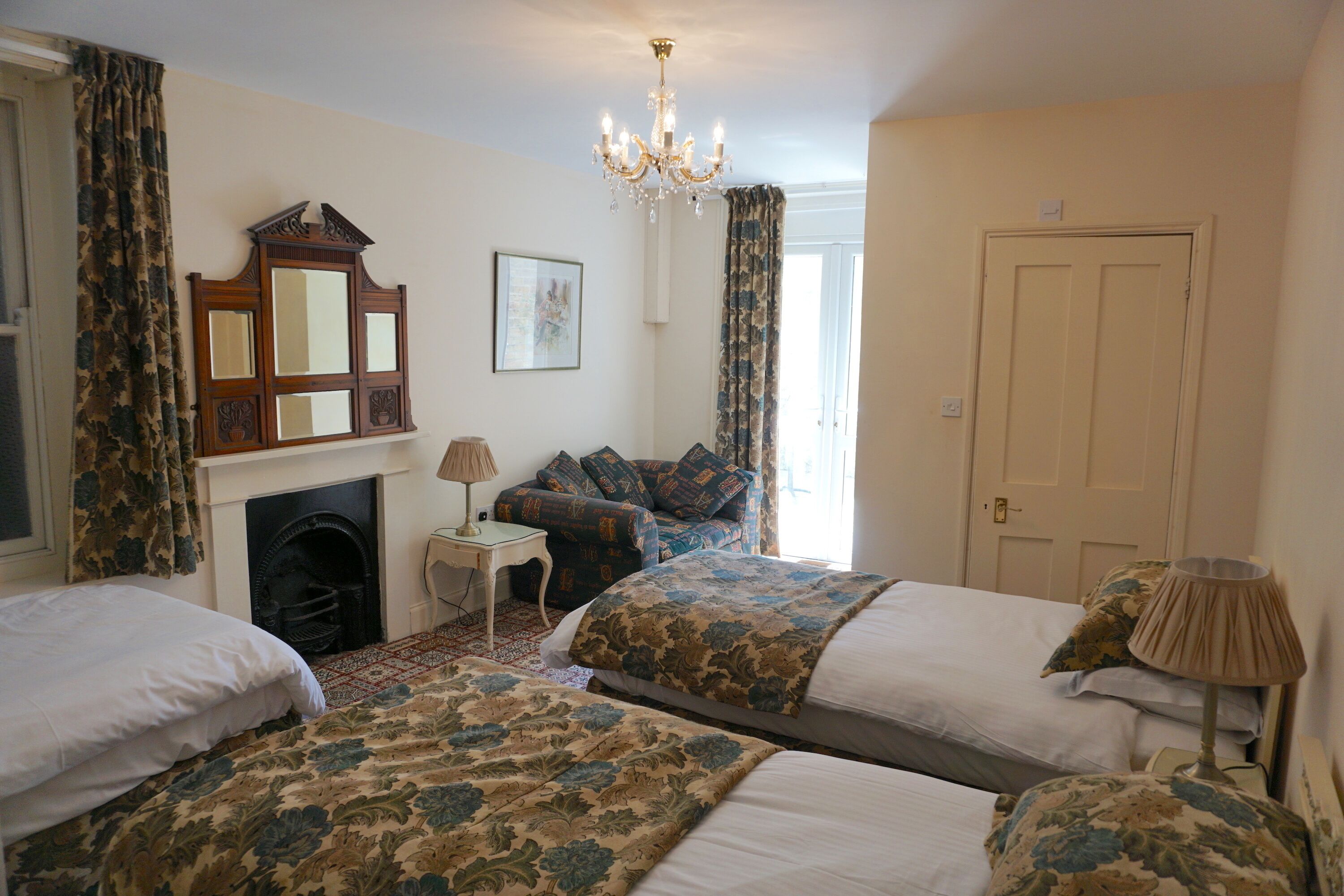 Una camera d'albergo con due letti, un camino, un lampadario e una porta.