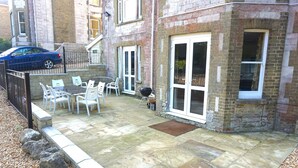 A patio with stone flooring, white chairs, a table, and a barbecue grill. - MANSION WITH SWIMMING POOL, GAMES ROOM, SEA VIEWS, SANDY BEACHES 2 MINS WALK (Ryde)
