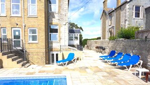 A pool area with blue lounge chairs, a stone wall, and a staircase leading to an upper level. - MANSION WITH SWIMMING POOL, GAMES ROOM, SEA VIEWS, SANDY BEACHES 2 MINS WALK (Ryde)