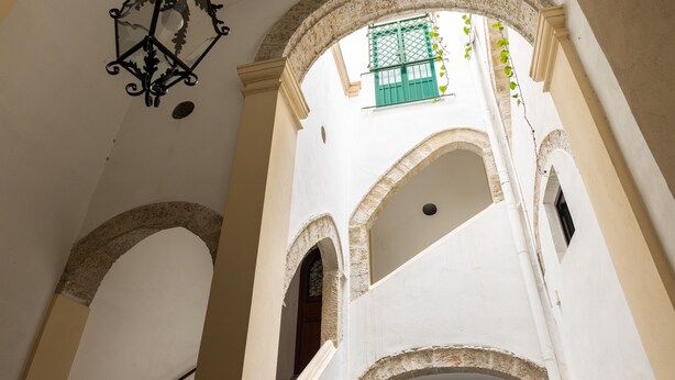 An interior view of a building with arched doorways and a hanging lantern.