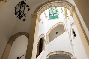 An interior view of a building with arched doorways and a hanging lantern. - Elegant, quiet, large apartment in Palazzo Mango, beautiful heart of old Palermo (Palermo)