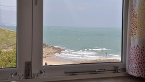 A window with a view of the ocean and a rocky beach.