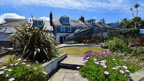 A residential area with houses, a garden with flowers, and a clear sky.