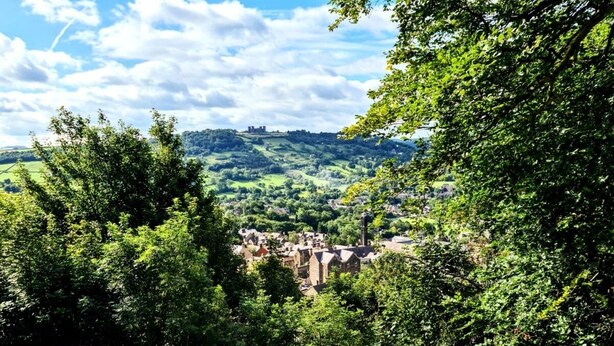 Eine Holzterrasse mit Blick auf ein Dorf und Hügel im Hintergrund.