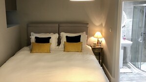 Ein Schlafzimmer mit einem großen Bett, zwei Nachttischen mit Lampen und einer Duschkabine aus Glas.