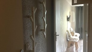 Un pasillo con un letrero de número, una puerta y una habitación con una silla y un escritorio.