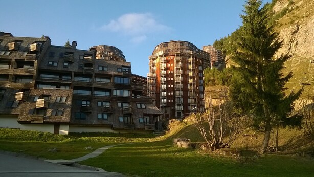 Un moderno edificio de apartamentos con varios balcones y un telesilla al fondo.