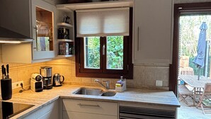Eine kleine Küche mit Spüle, Geschirrspüler und einem Fenster mit Jalousien.