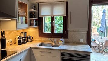 Cocina compacta con lavamanos, lavavajillas y ventana con persianas.