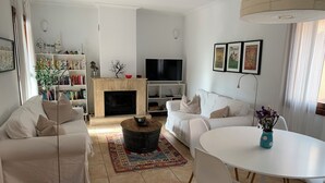 Ein modernes Wohnzimmer mit Kamin, weißen Sofas, einem Fernseher und einem Essbereich.