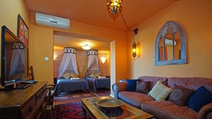 Ein Zimmer mit zwei Betten, einem Schlafsofa, einem Holztisch und einem Spiegel.