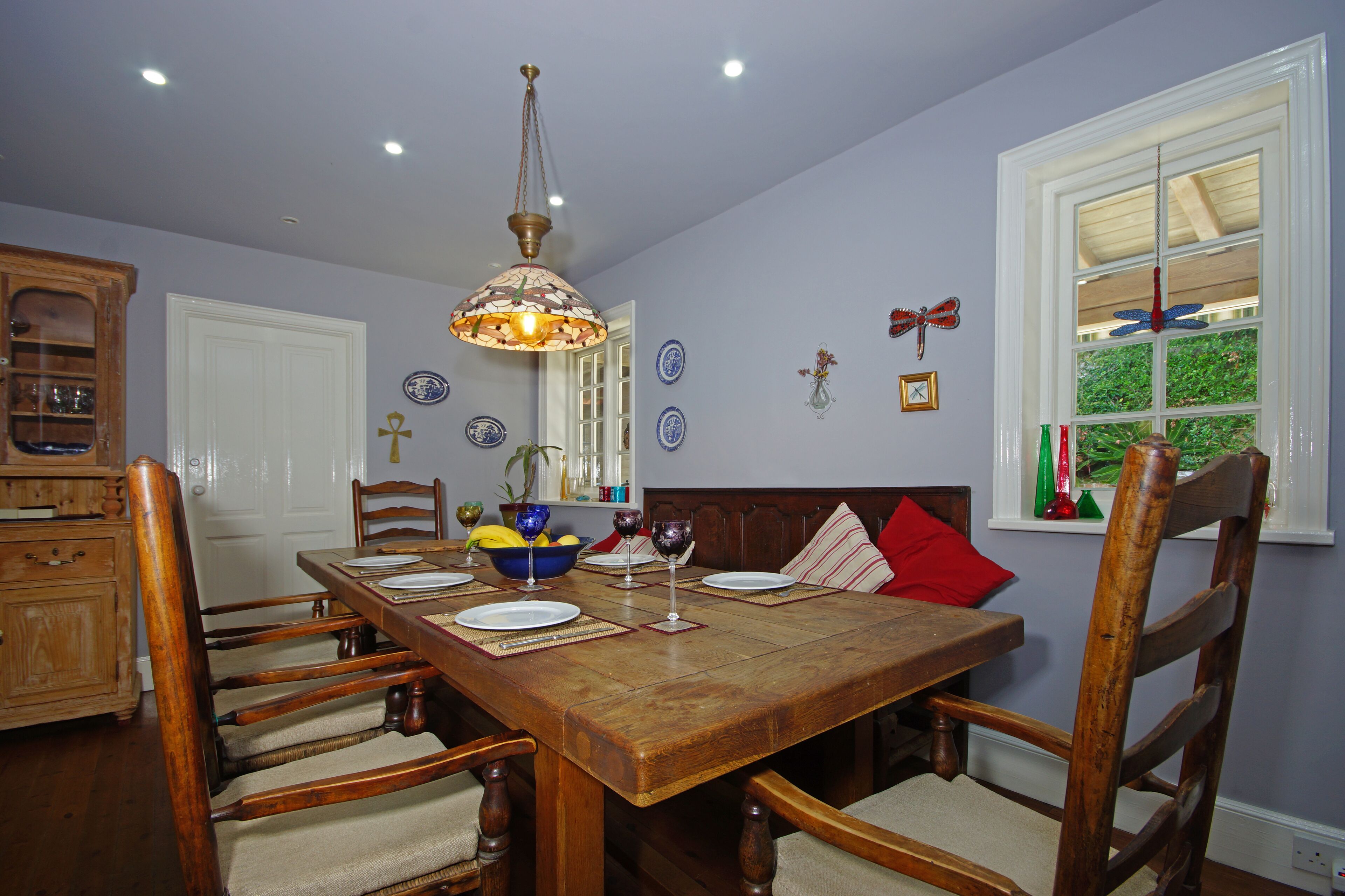 Un comedor con mesa de madera, sillas y una lámpara colgante.
