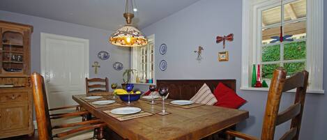 Un comedor con mesa de madera, sillas y una lámpara colgante.