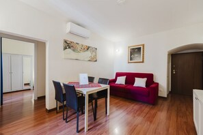 Una habitación con una mesa de comedor, sillas, un sofá rojo y un armario blanco.