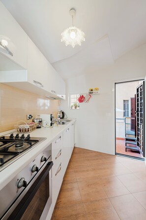 A modern kitchen with white cabinets, a gas stove, and a hanging light fixture.