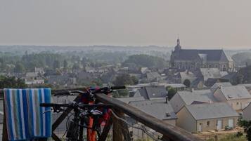 A bicycle leaning against a wooden fence overlooking a town with a prominent church in the background.