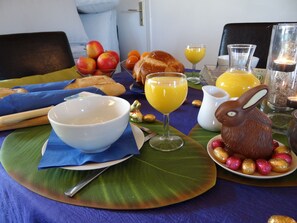 A breakfast table with a bowl, croissant, orange juice, and chocolate eggs. - Le Moulin Géant (Rochefort-sur-Loire)