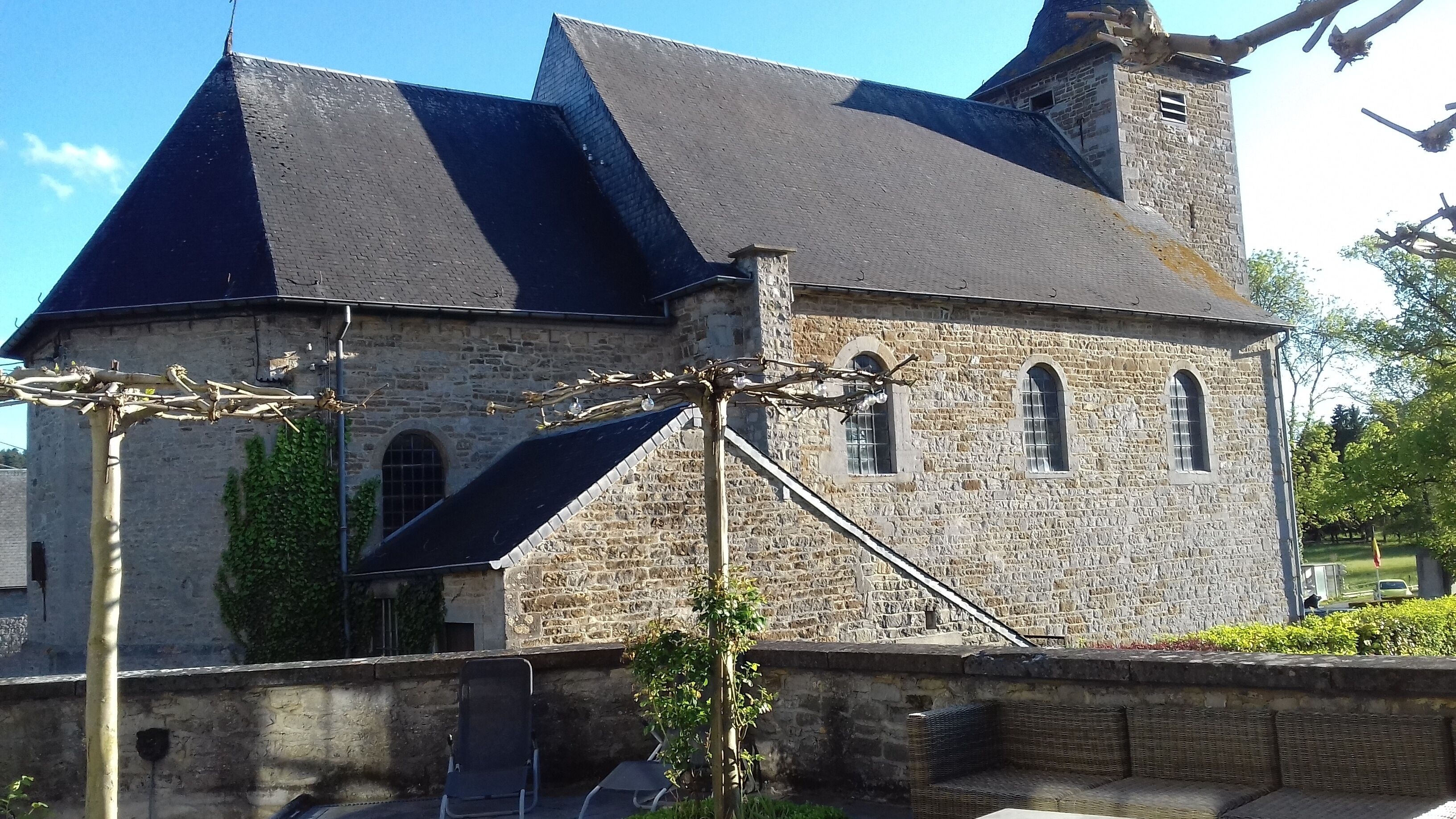 A stone building with a steeply pitched roof, arched windows, and a chimney.
