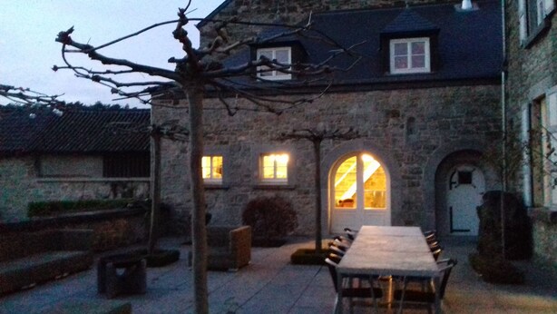 A stone building with a dining area featuring a long table and benches, a small arched window, and a tree in the foreground. - charming country cottage for rent  (Ave et Auffe)