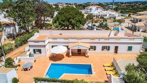 A hotel with a swimming pool, outdoor seating, and a covered patio area. - Villa Bia OCV - Private Pool (Albufeira)
