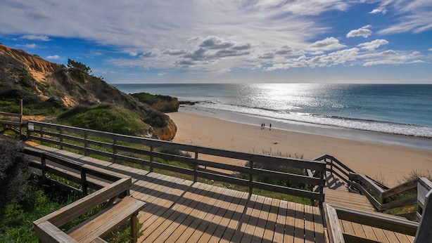 A wooden boardwalk leading to a beach with a rocky cliff on one side and a clear sky above. - Villa Bia OCV - Private Pool (Albufeira)