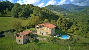 A stone house with a red-tiled roof, a swimming pool, and a view of the surrounding green hills and mountains. - Cottage, private pool, beautiful mountain views, WIFI. (nicciano)
