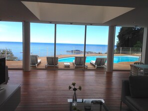 Un vaste balcon doté d’une piscine, de chaises longues et offrant une vue sur la mer.