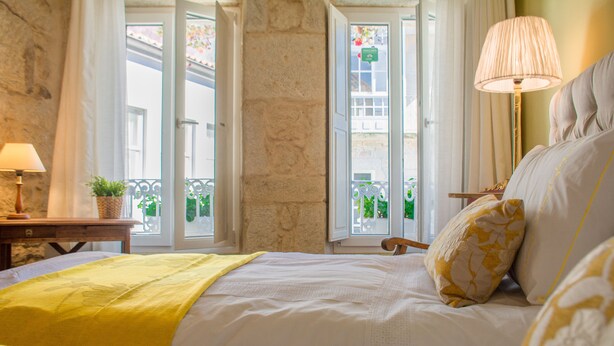 A hotel room with a bed, a lamp, a window with a view of the outside, and a small table with a plant. - Anchor House floor in Walls with wifi (Muros, A Coruña)
