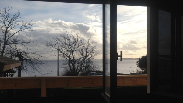 A view from a room with a large window overlooking a body of water, a wooden deck, and bare trees. - 40 meters from the beach, windows on the Arcachon "basin" (Arès)