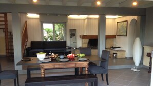 A dining area with a table set for four, a black sofa, and a kitchen in the background. - 40 meters from the beach, windows on the Arcachon "basin" (Arès)