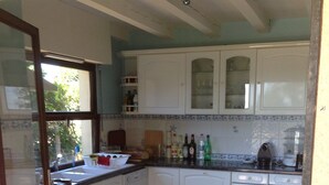 A kitchen with white cabinets, a tiled backsplash, and a window overlooking greenery. - 40 meters from the beach, windows on the Arcachon "basin" (Arès)