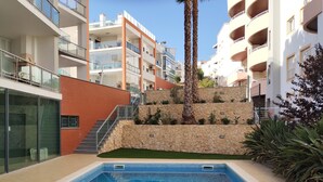 Un edificio moderno con piscina, una escalera y una palmera.