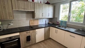 Una cocina moderna con armarios de madera, encimera negra y una ventana que deja entrar luz natural.