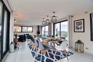 Un comedor moderno con una mesa grande, sillas y lámparas colgantes.
