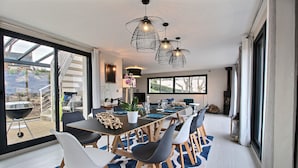 Un comedor moderno con una mesa larga, sillas blancas y grises, y un tapete azul estampado.