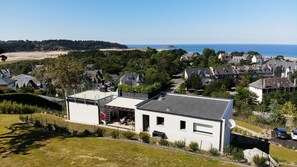 Una casa moderna con techo plano, ventanas amplias y vista al mar.