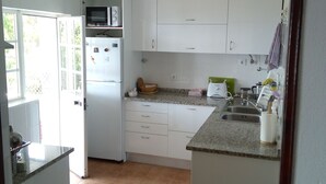 A kitchen with white cabinets, a microwave, a refrigerator, and a sink. - Rustic house, sea view, 6 people, terrace with barbecue.  (Sesimbra)