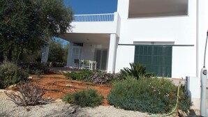 A modern white building with a balcony, surrounded by a garden with various plants and flowers. - New Villa With Private  Pool At Walking Distance From The Centre/Beach (Santanyí)