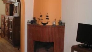 A living room with a fireplace, a television on a stand, and a wooden floor.