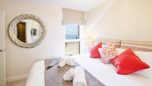 Una habitación de hotel con cama, un espejo redondo, una ventana con vistas y una puerta.