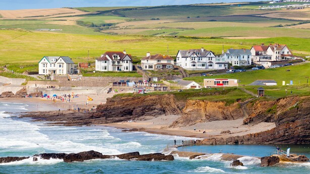 A coastal town with houses along the beach, rocky cliffs, and a clear view of the sea.