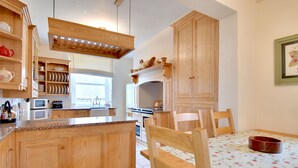A kitchen with wooden cabinets, a granite countertop, and a dining table with chairs.