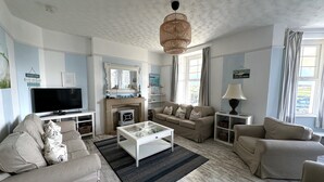 A living room with a sofa, a coffee table, a TV, and a fireplace.
