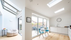 A modern kitchen with a sink, a dining area with blue chairs, and a sofa. - Seawood House, Wells-next-the-Sea, Norfolk (Wells-next-the-Sea)