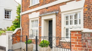 A brick house with white window shutters, a black metal fence, and a white door. - Seawood House, Wells-next-the-Sea, Norfolk (Wells-next-the-Sea)