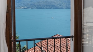 Vista d'un llac amb una barca, envoltat de turons i un edifici amb teulada vermella.