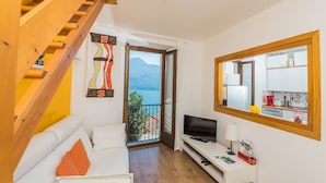 Un saló modern amb escala de fusta, televisió de pantalla plana, sofà i un balcó amb vista a la muntanya.